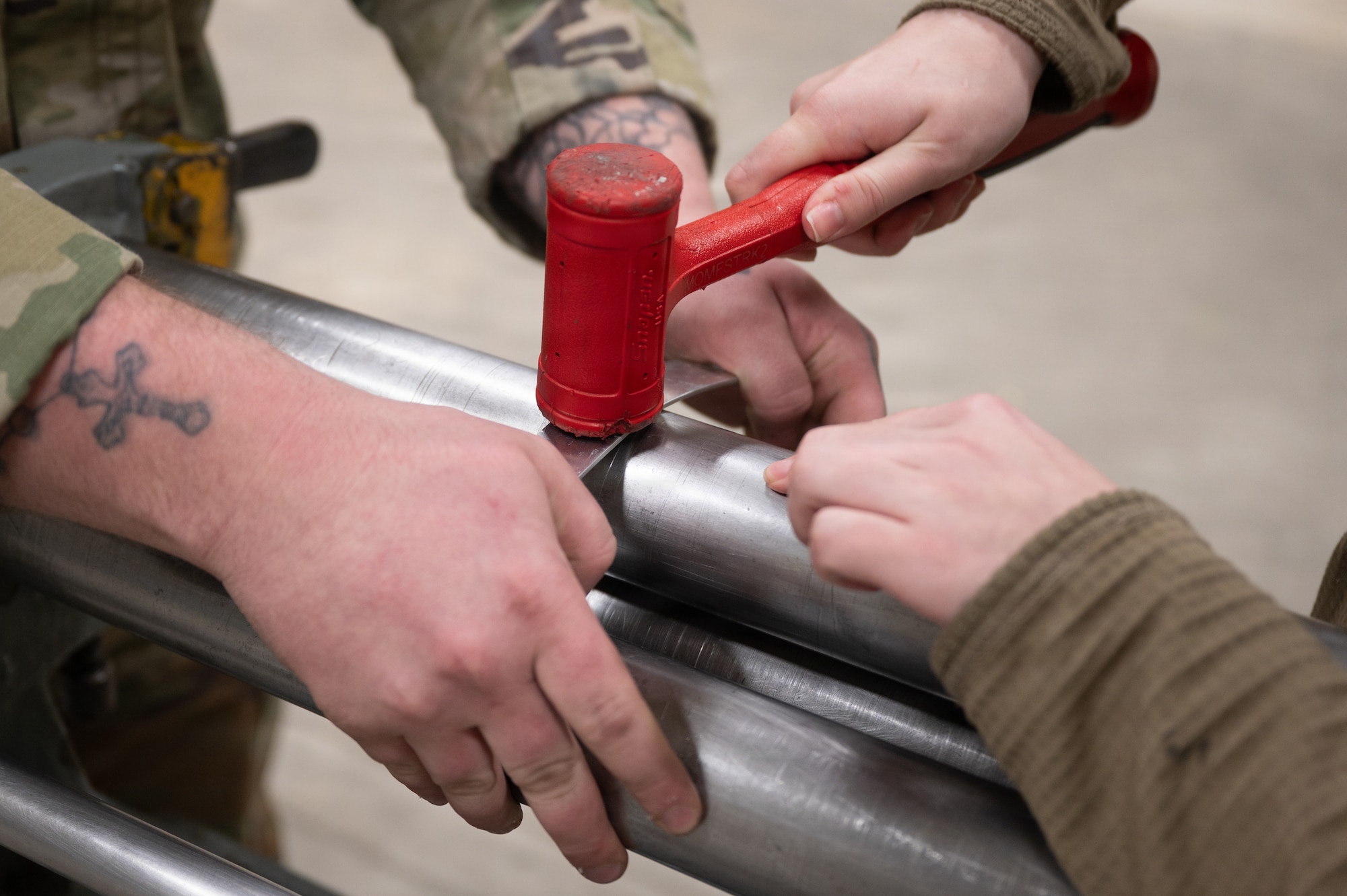U.S. Air Force Airman 1st Class Jeremy Lizotte, left, 35th Maintenance Group aircraft structural maintenance journeyman, assists Senior Airman Malela Peralta, 35th Maintenance Group aircraft structural maintenance Journeyman, with hammering a sheet metal component at Misawa Air Base
