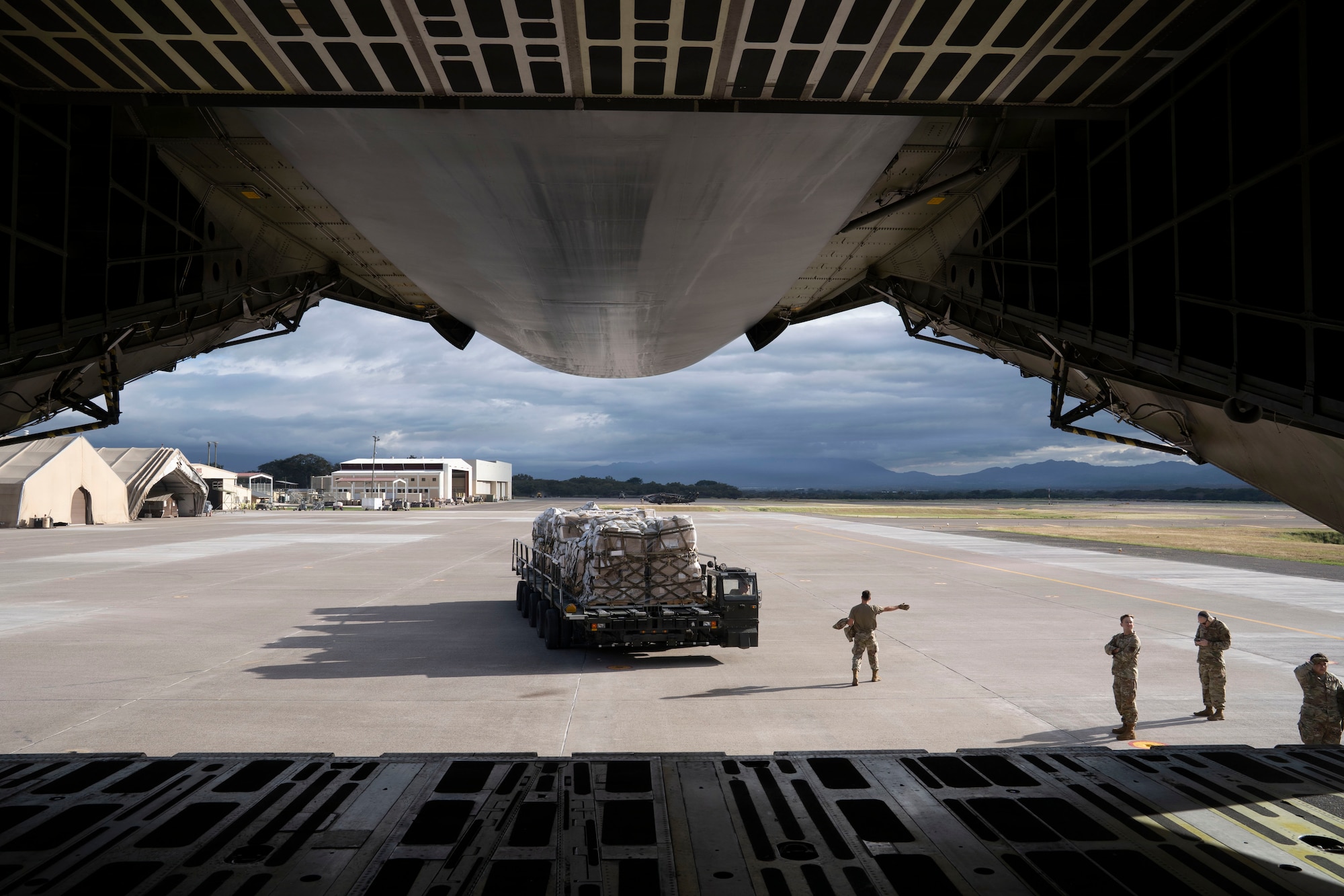 Service members offload cargo from a military airplane
