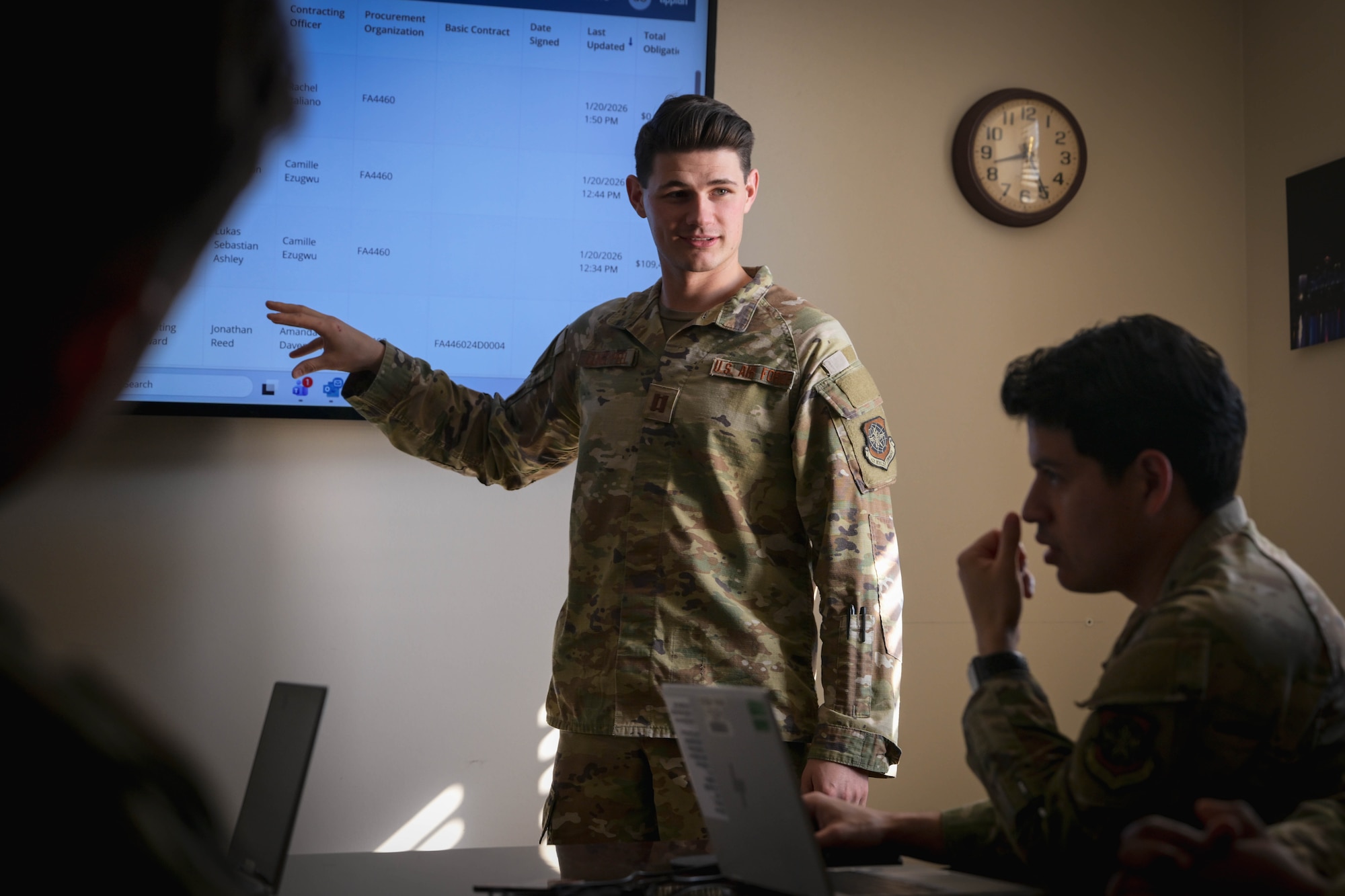 A man in uniform gives a presentation to other people in uniform.