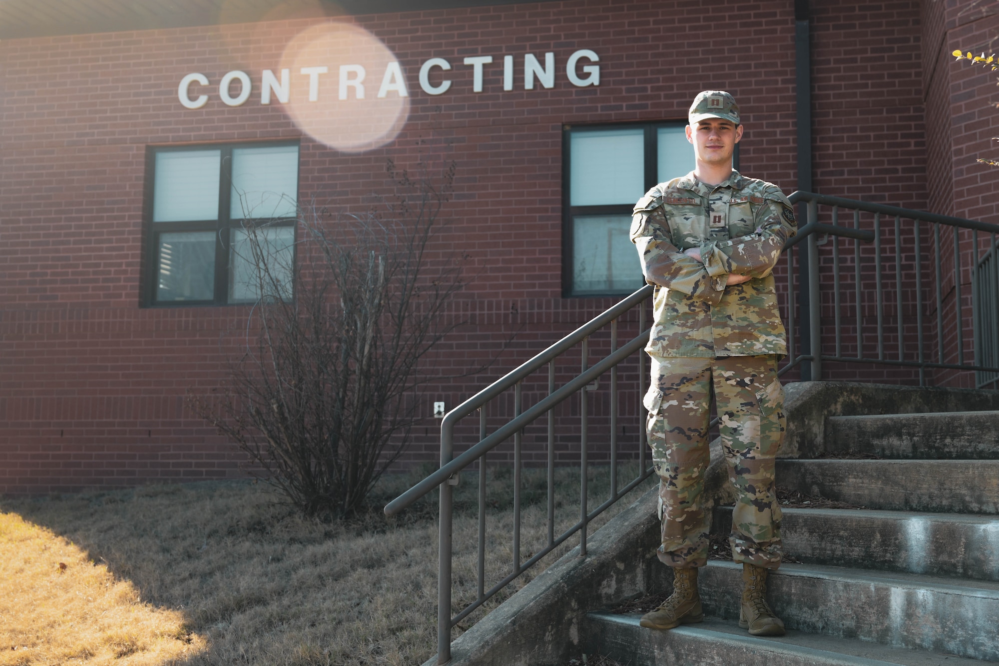 A man in uniform stands on a flight of stairs in front of a "contracting" sign.