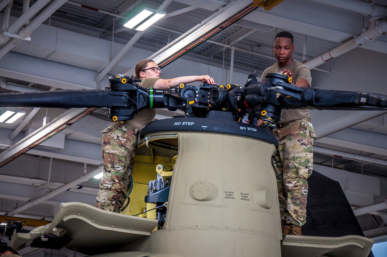 U.S. Army Spc. Kaitlin Cavanaugh and Sgt. Omar Sewell conduct maintenance on the forward rotor of a CH-47 Chinook helicopter, which was battle damaged from a hard landing while serving in Iraq, in the maintenance bay of the Connecticut National Guard's 1109th Theater Aviation Support Maintenance Group in Groton, Conn. June 22, 2021.