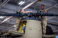 U.S. Army Spc. Kaitlin Cavanaugh and Sgt. Omar Sewell conduct maintenance on the forward rotor of a CH-47 Chinook helicopter, which was battle damaged from a hard landing while serving in Iraq, in the maintenance bay of the Connecticut National Guard's 1109th Theater Aviation Support Maintenance Group in Groton, Conn. June 22, 2021.