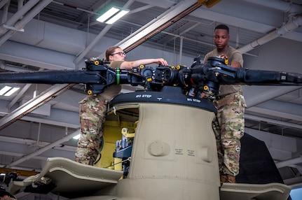U.S. Army Spc. Kaitlin Cavanaugh and Sgt. Omar Sewell conduct maintenance on the forward rotor of a CH-47 Chinook helicopter, which was battle damaged from a hard landing while serving in Iraq, in the maintenance bay of the Connecticut National Guard's 1109th Theater Aviation Support Maintenance Group in Groton, Conn. June 22, 2021.