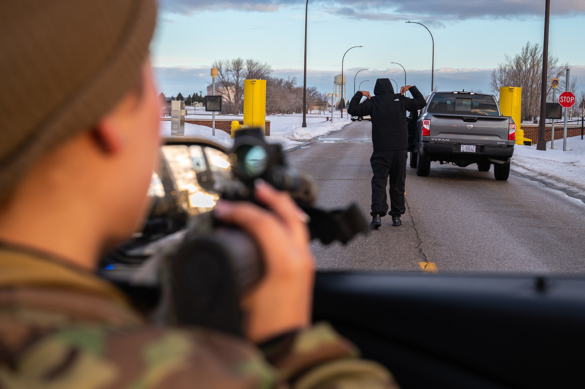 A photo of a military member pointing a gun at a man.