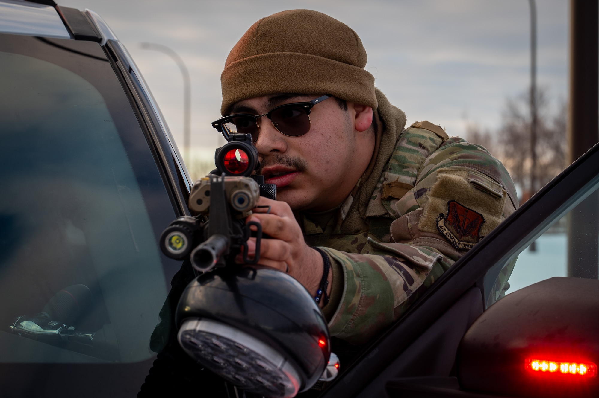 A photo of a man holding a gun against a car door.