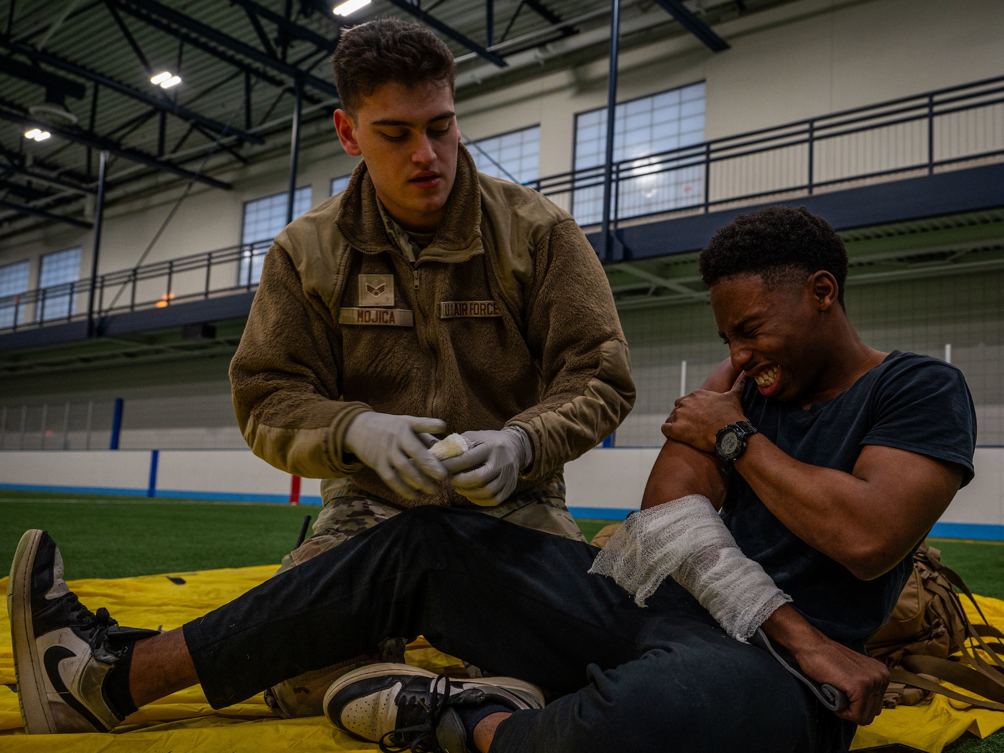A photo of a military member giving medical attention to a man on the floor.