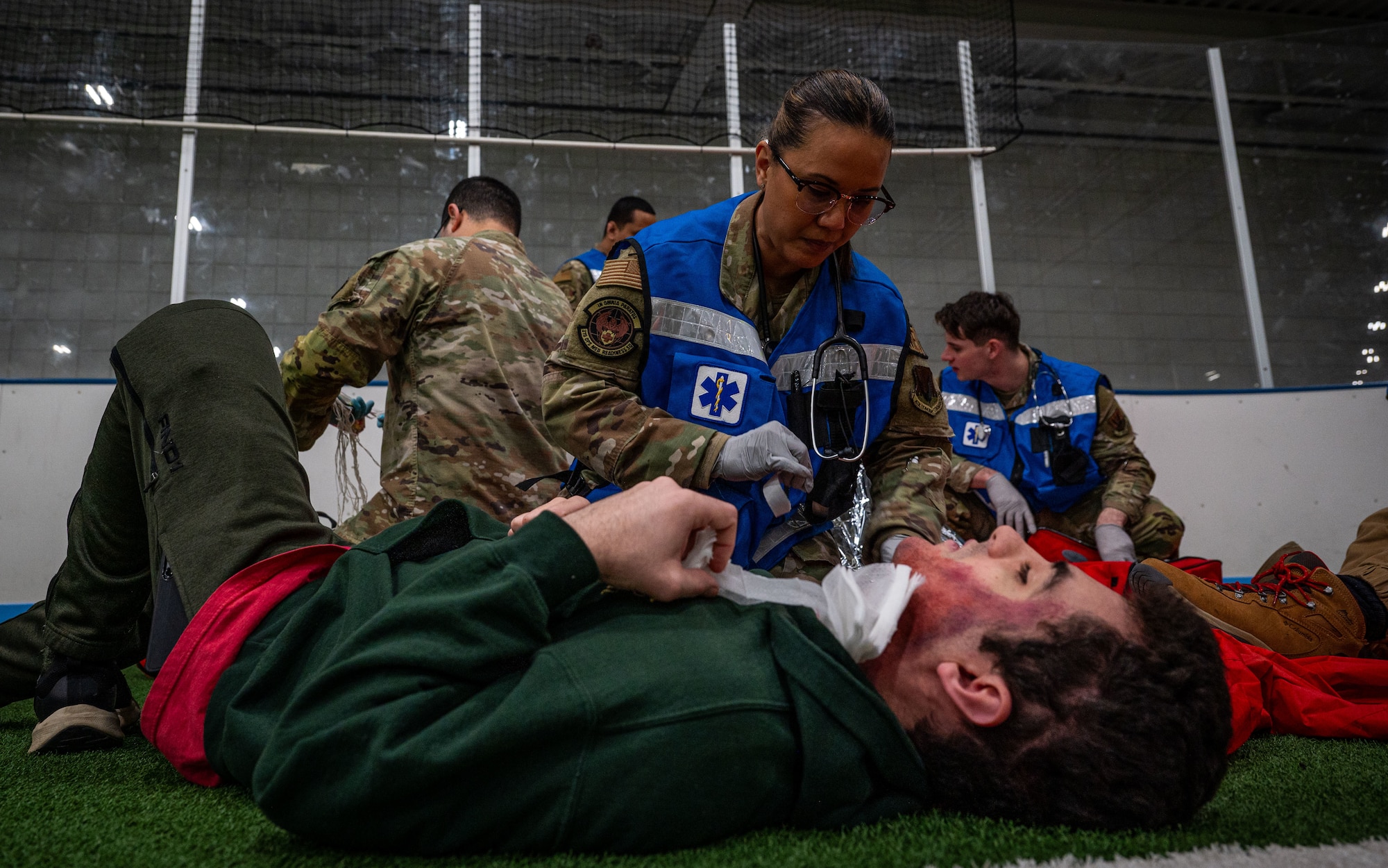 A photo of a military member giving medical to a man on the floor.