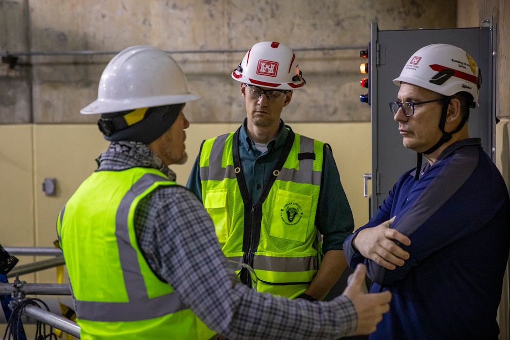 Ron Beyer (right), project manager, U.S. Army Corps of Engineers, Omaha District, and Kevin Vogel (center), Fort Peck Dam project engineer, review progress on the butterfly valve rehabilitation project, Dec. 10, 2025, at the Fort Peck Dam in Montana.