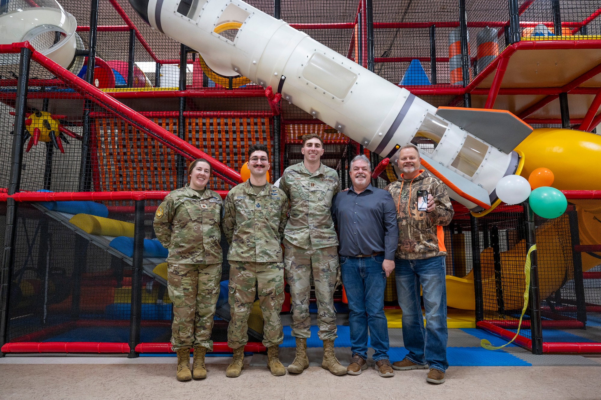 From left, U.S. Space Force Major Lauren Lauritzen; U.S. Space Force SSgt Noah Buckley; U.S. Air Force Capt. Eric Curia; Robert Bertels; Scott Holmquist and Sean Hagan, 10th Space Warning Squadron members, pose for a photo in front of the community center play area at Cavalier Space Force Station, North Dakota, Jan. 9, 2026.