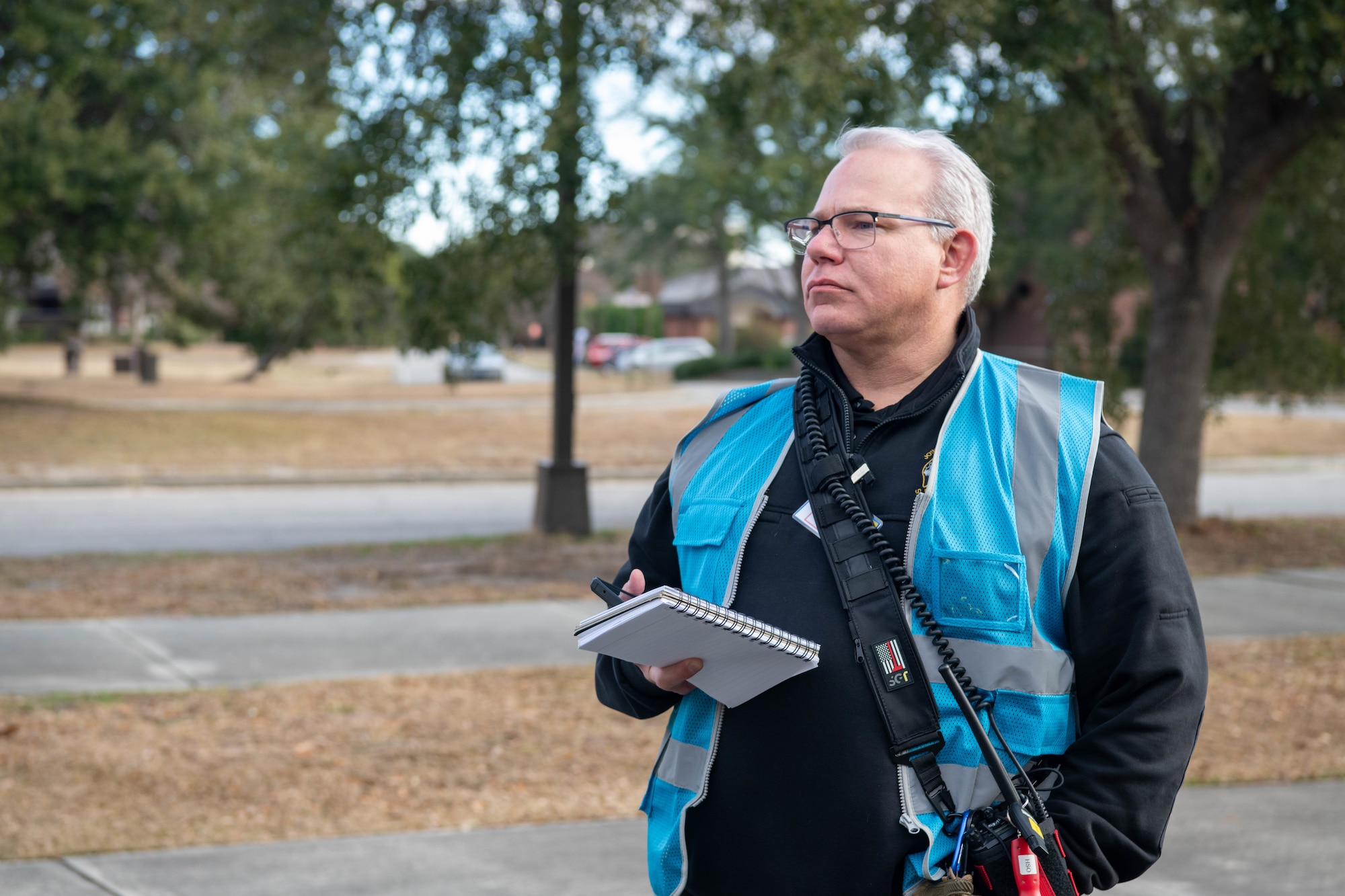 A photo of a man in a blue vest standing outside.