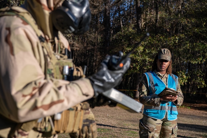 A photo of a man in a blue vest standing outside.