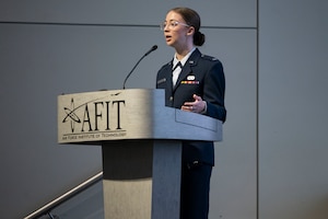 1st Lt. Adrianna Blenkush stands at a podium speaking at a conference.