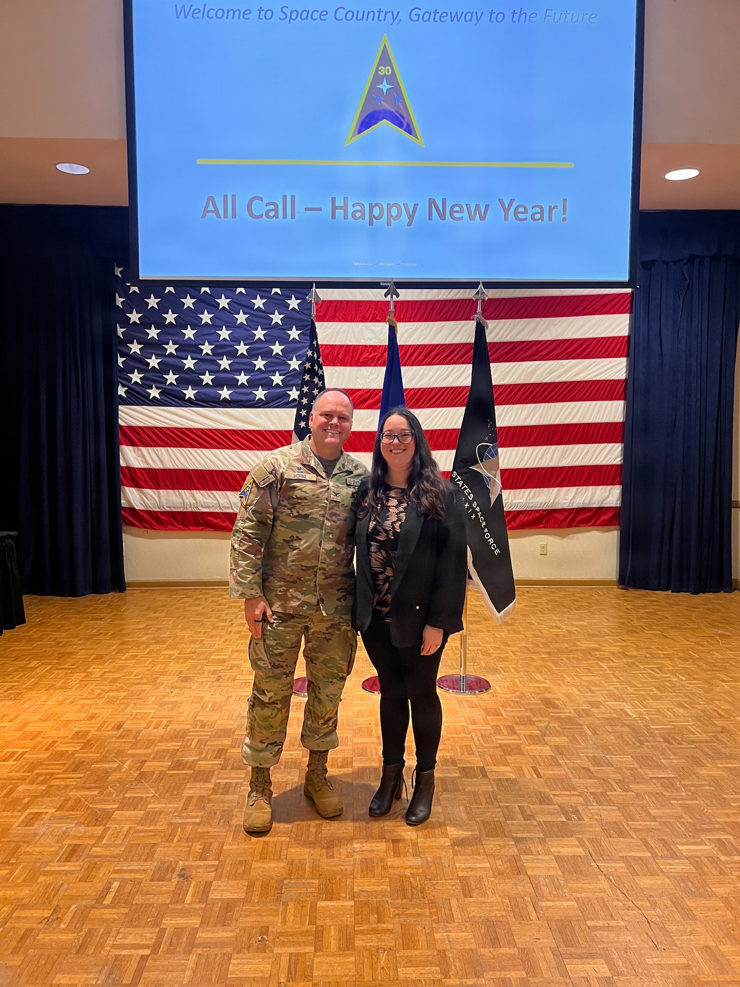 2 people stand on a stage and smile for a photo