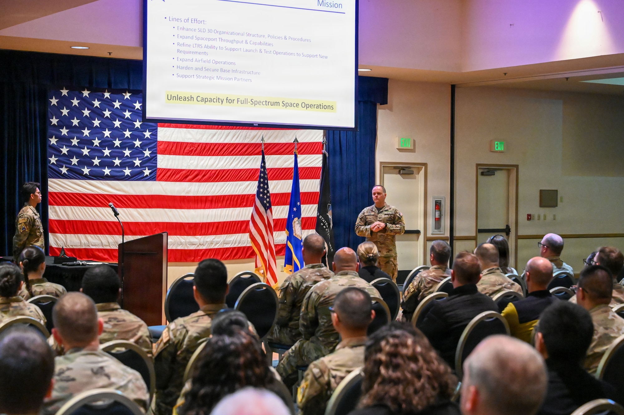 a man stands on a stage and speaks to a crowd