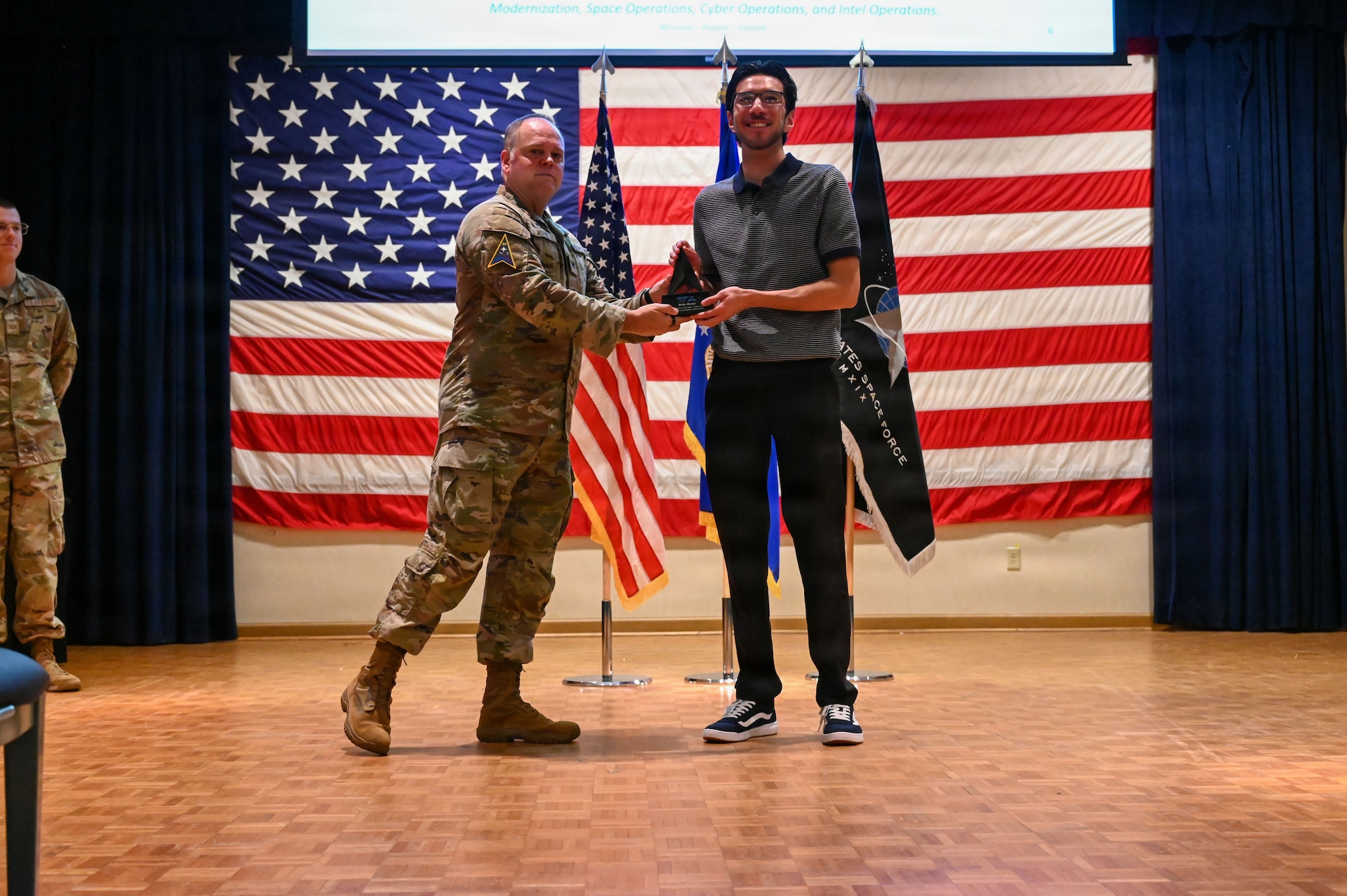 2 people stand on a stage and smile for a photo