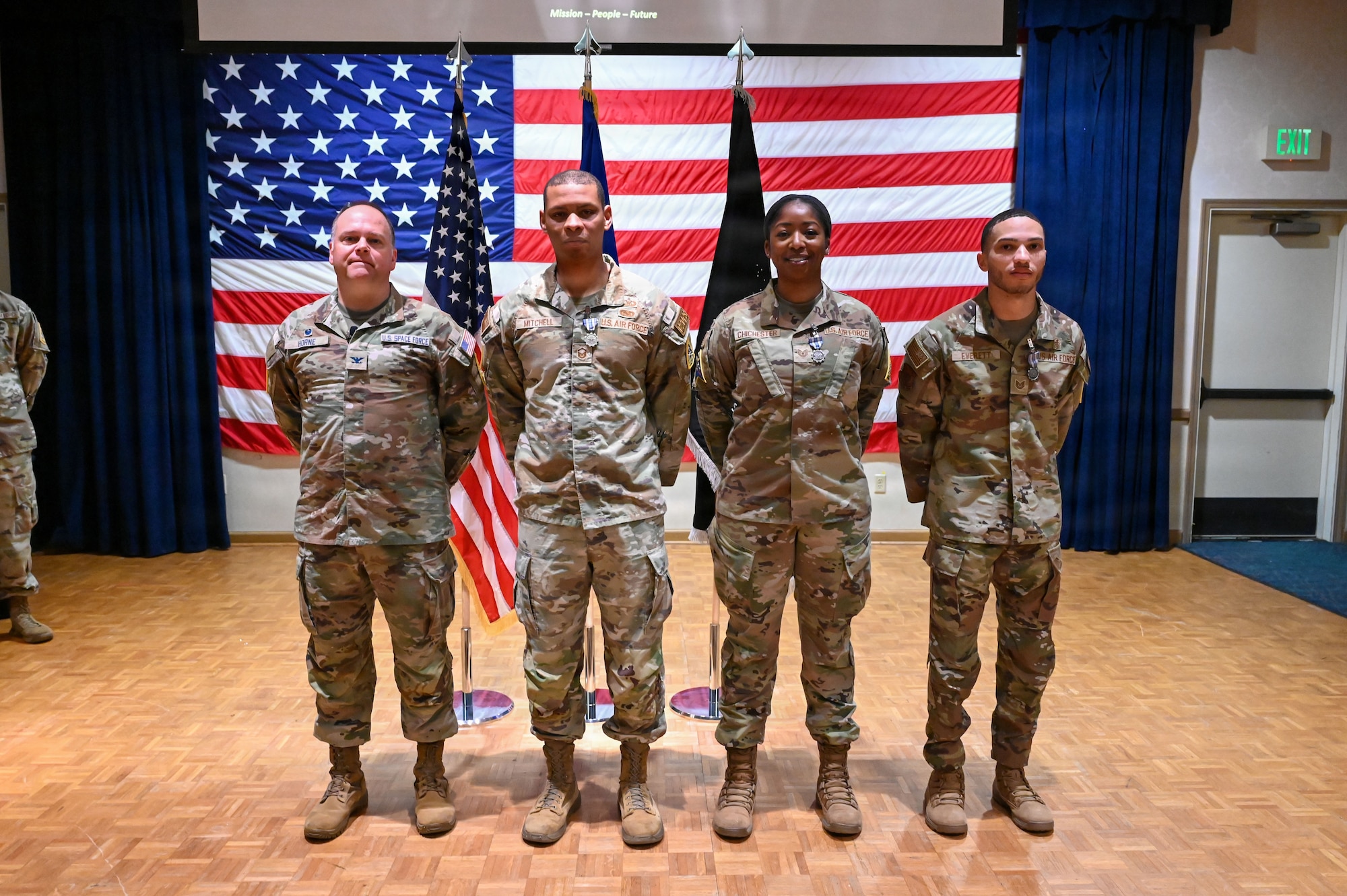 four people stand on a stage and smile for a photo