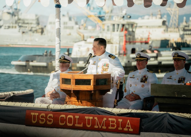 JOINT BASE PEARL HARBOR-HICKAM, Hawaii (Nov. 18, 2025) - Cmdr. Brad Foster, outgoing commanding officer of Los Angeles-class fast-attack submarine USS Columbia (SSN 771), gives remarks during the change of command ceremony for Columbia at Joint Base Pearl Harbor-Hickam, Hawaii, Nov. 18, 2025. Columbia is assigned to Submarine Squadron 7 and is capable of supporting various missions, including anti-submarine warfare, anti-surface ship warfare, strike warfare, special operations forces support, and intelligence, surveillance, and reconnaissance. (U.S. Navy photo by Mass Communication Specialist 2nd Class Nicholas Russell)