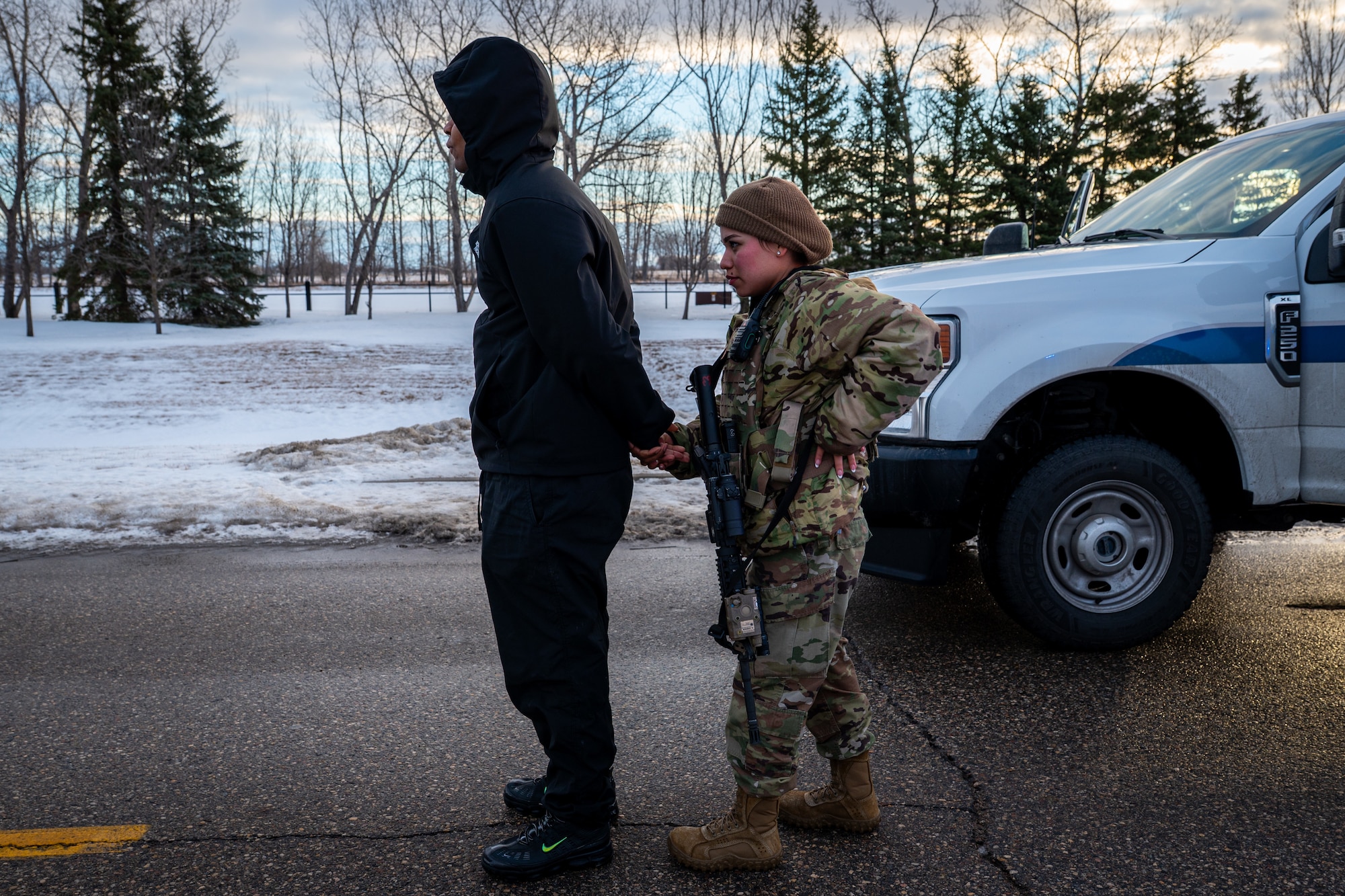 A photo of a military member taking a man into custody and putting on handcuffs.