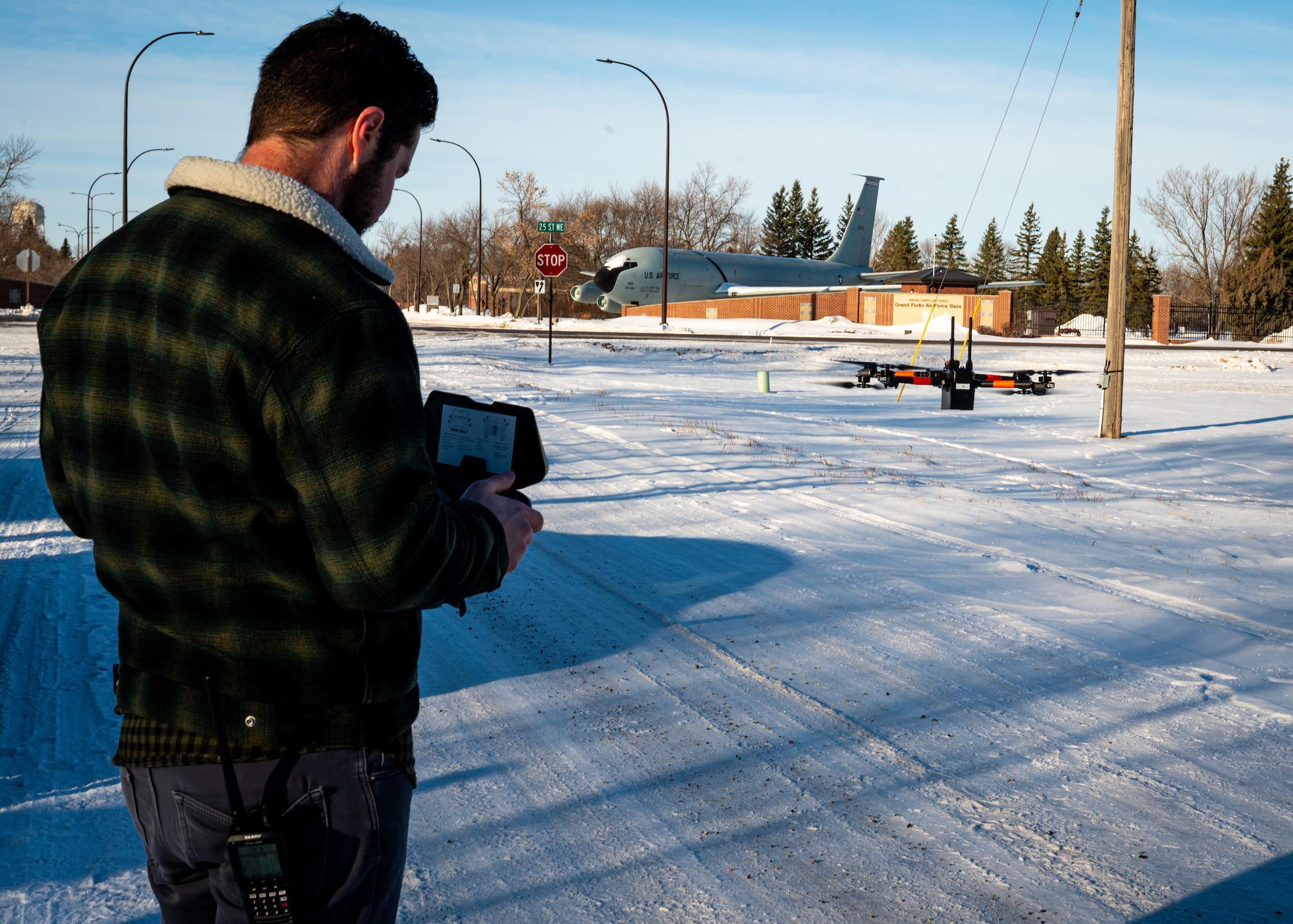 A photo of a man controlling a small-unmanned aircraft in from of him.