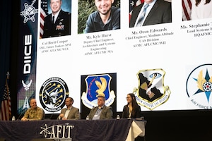 Leader sit on stage at a panel event during a symposium.