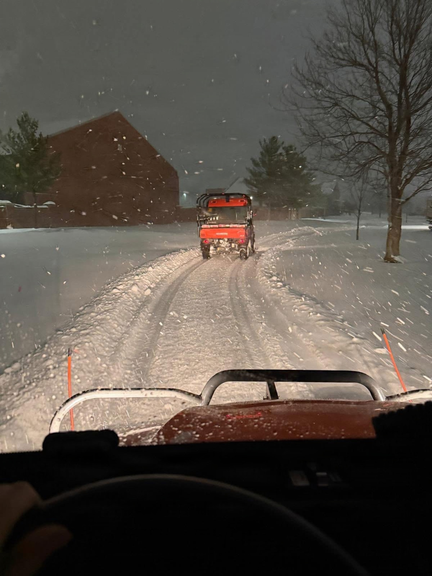 A side by side follows behind a side by side plowing side walks.