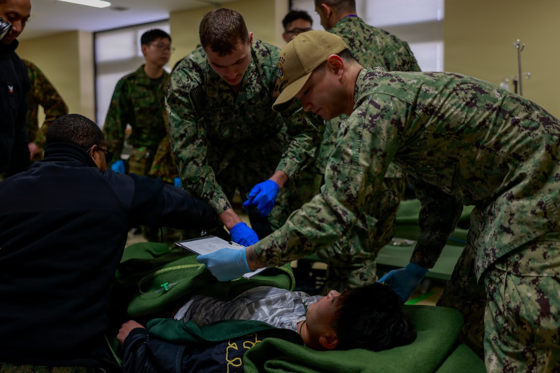 U.S. Sailors with the Naval Family Branch Clinic Iwakuni secure a simulated casualty to a stretcher during exercise Nankai Rescue 2026 at the Lotus Cultural Center, Iwakuni, Japan, Jan. 24, 2026. Exercise Nankai Rescue 2026 is a full-scale exercise focused on enhancing the bilateral coordination between the U.S. and Japan in support of humanitarian and disaster relief efforts. (U.S. Marine Corps photo by Lance Cpl. Isaac De Leon)