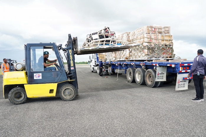A forklift lifts a loaded pallet from its place on the back of a cargo loader.
