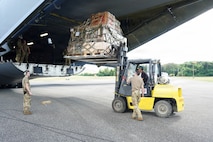 A forklift lifts a pallet loaded with cargo into a Boeing KC-46 Pegasus aircraft.