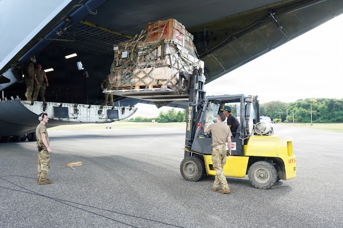 A forklift lifts a pallet loaded with cargo into a Boeing KC-46 Pegasus aircraft.