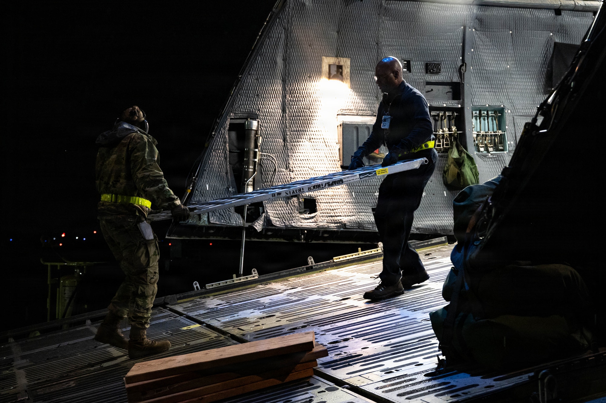 Airmen carry a piece of a ramp out of an aircraft.
