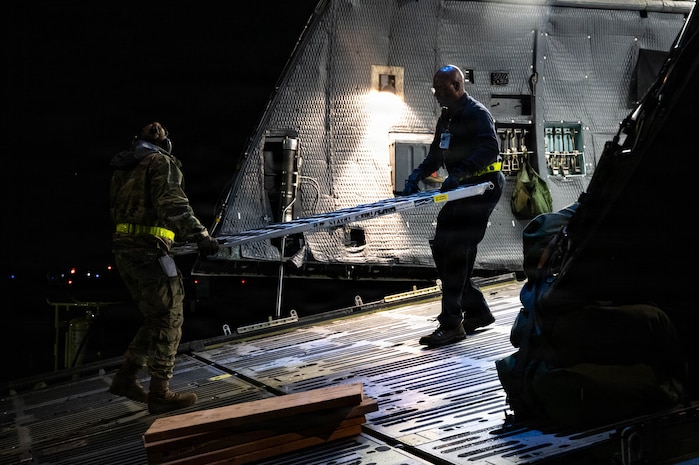 Airmen carry a piece of a ramp out of an aircraft.