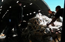 Airmen push a pallet of cargo onto a KC-46A Pegasus aircraft