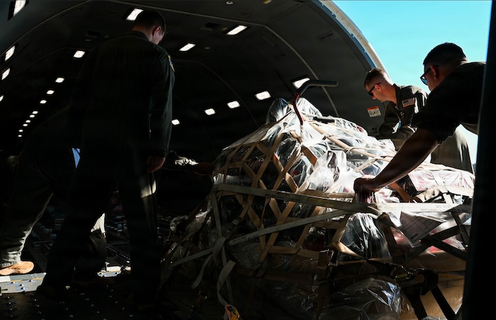 Airmen push a pallet of cargo onto a KC-46A Pegasus aircraft