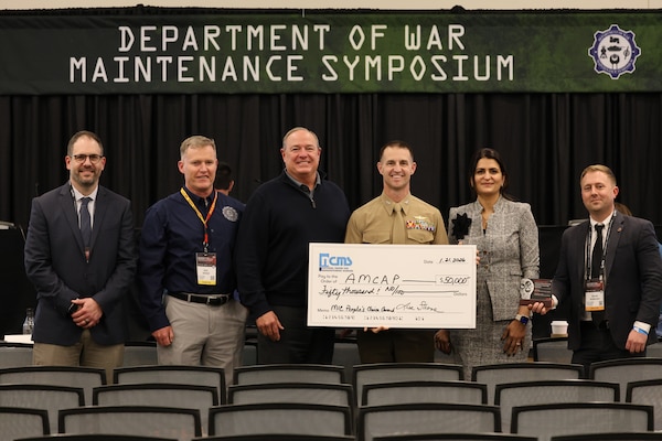 Col. Nicolas Lozar, commanding officer, Marine Depot Maintenance Command, and team pose with the check presented after winning the People's Choice Award at the 2026 Maintenance innovation Challenge, in Phoenix Arizona during the Department of War Maintenance Symposium.