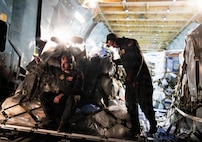 Loadmasters guide an aircraft loader into a C-5M Super Galaxy