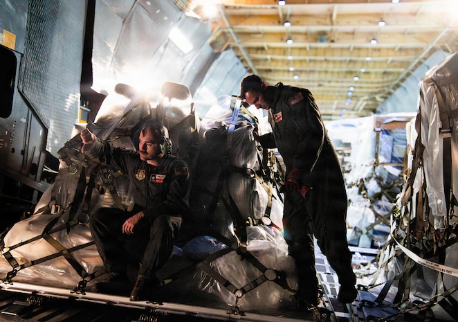 Loadmasters guide an aircraft loader into a C-5M Super Galaxy