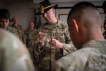 U.S. Army Command Sgt. Maj. Tim Englund, a master spur holder assigned to the 303rd Cavalry Regiment, Washington National Guard, inspects a gold spur during a ceremony at Camp Lemonnier, Djibouti, Jan. 9, 2026. Englund has earned both silver and gold spurs and has helped facilitate multiple Spur Rides throughout his career. Photo by Sgt. 1st Class Kenneth Tucceri.