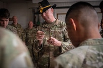 U.S. Army Command Sgt. Maj. Tim Englund, a master spur holder assigned to the 303rd Cavalry Regiment, Washington National Guard, inspects a gold spur during a ceremony at Camp Lemonnier, Djibouti, Jan. 9, 2026.