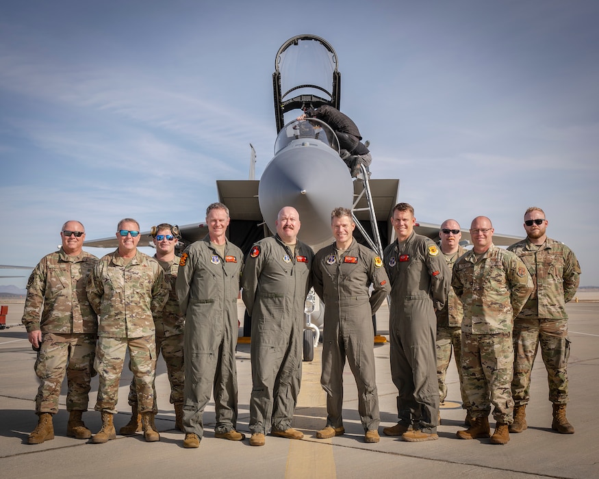 Military members stand in front of a F-15 Eagle