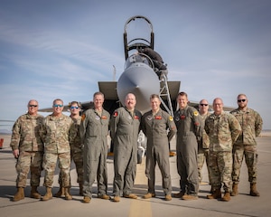Military members stand in front of a F-15 Eagle