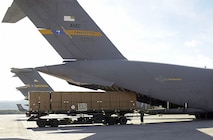 Tan containers are loaded into the back of a C-17A Globemaster III aircraft