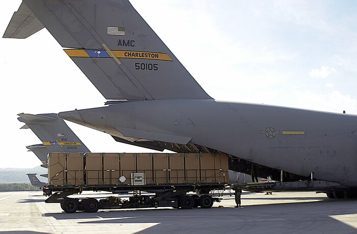 Tan containers are loaded into the back of a C-17A Globemaster III aircraft