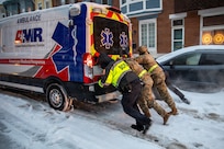 Maryland Army National Guard Soldiers from 1st Battalion, 175th Infantry Battalion and paramedics from Old Town Fire Station push an ambulance out of the snow in Baltimore, Jan. 25, 2026.