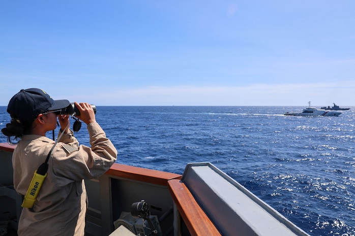 U.S. Navy Ensign Thara Venkateswaran reads flag signals aboard Arleigh Burke-class guided-missile destroyer USS John Finn (DDG 113) during a flag hoist drill with Philippine Coast Guard Gabriela Silang-class frigate BRP Gabriela Silang (8301) and Philippine Navy Jose Rizal-class frigate BRP Antonio Luna (FF151) during the Maritime Cooperative Activity (MCA) in the Philippines’ Exclusive Economic Zone, Jan. 25, 2026.