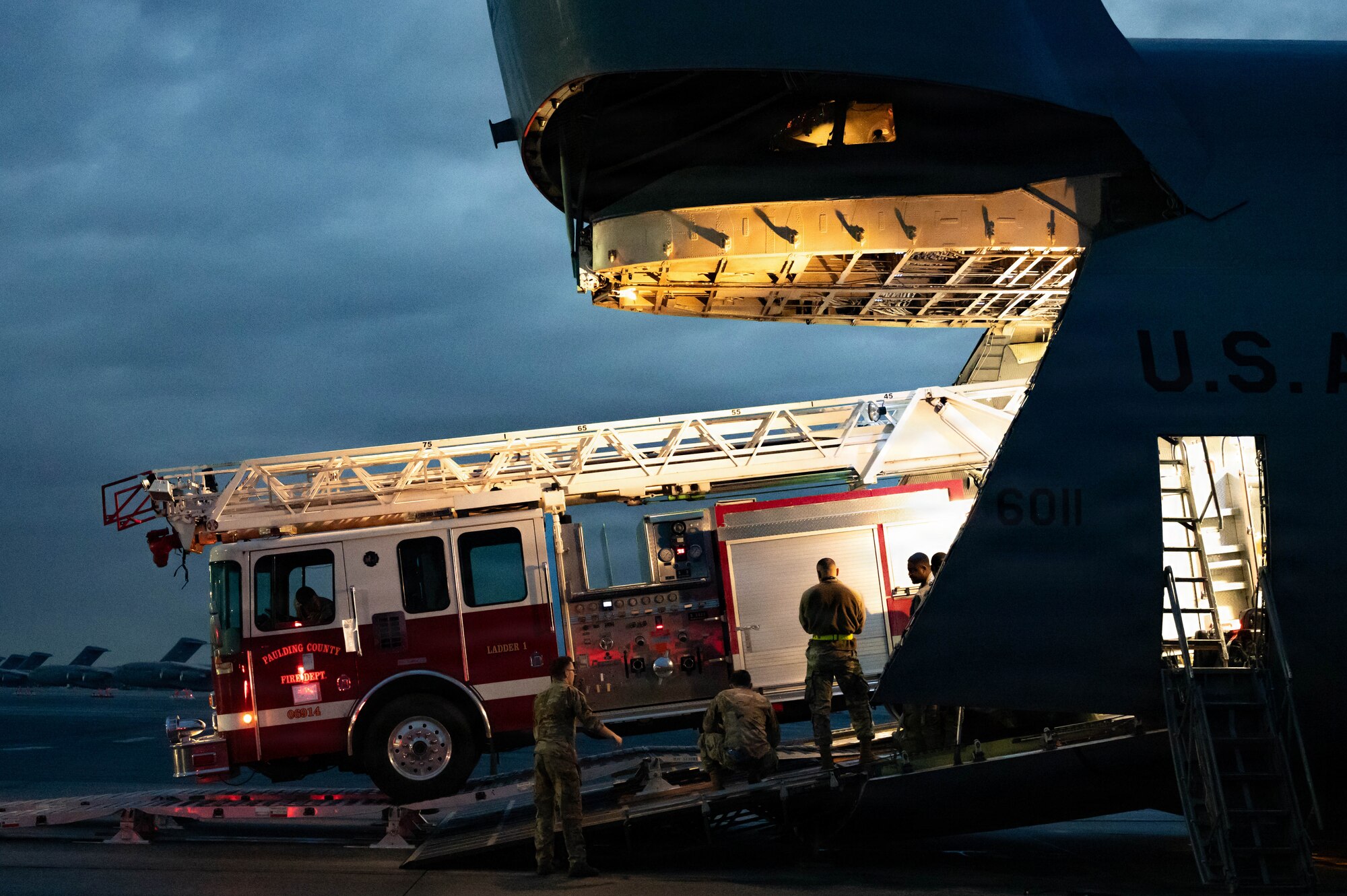A firetruck backs into a C-5 Galaxy aircraft.