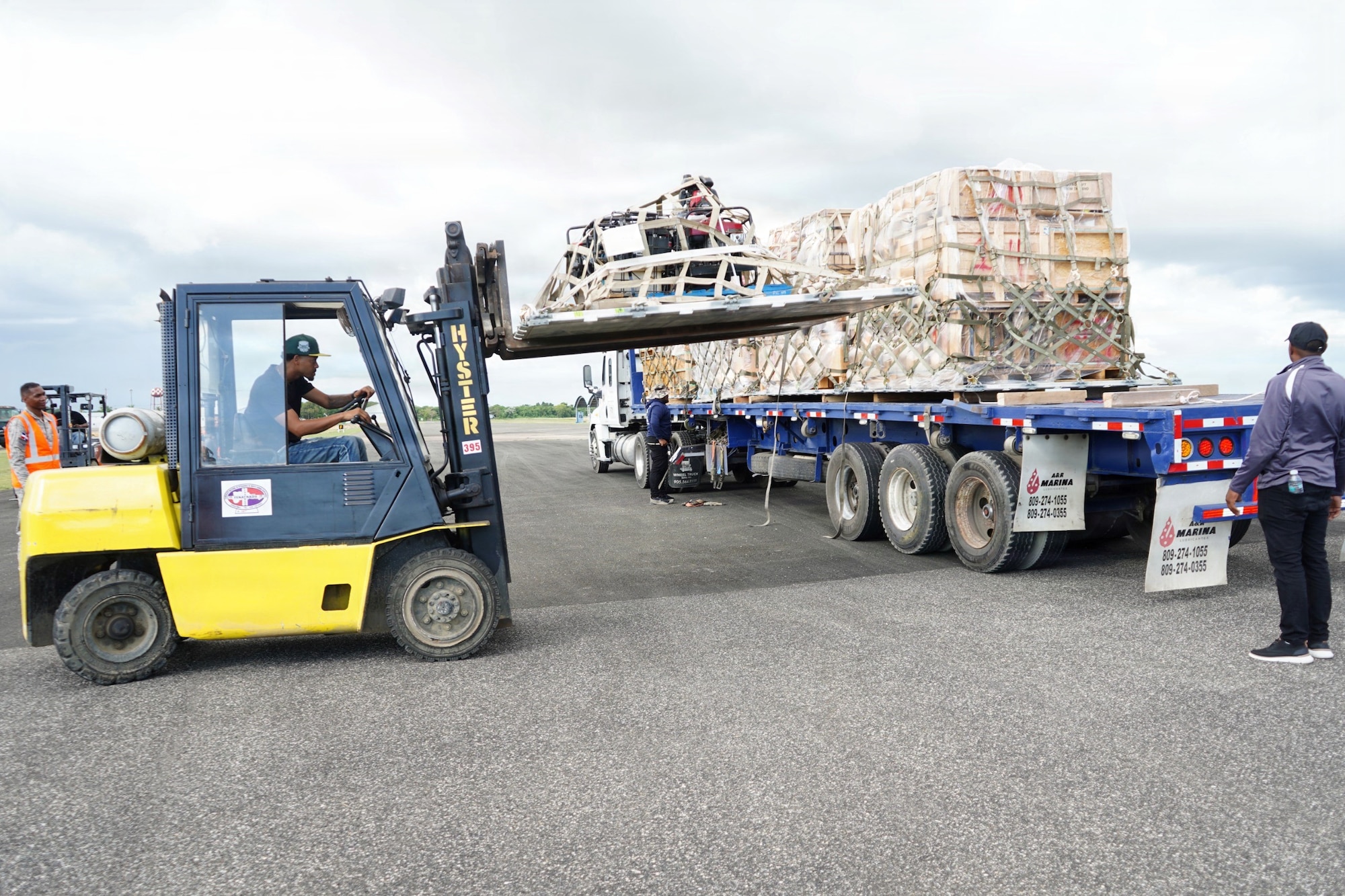 A forklift lifts a loaded pallet from its place on the back of a cargo loader.
