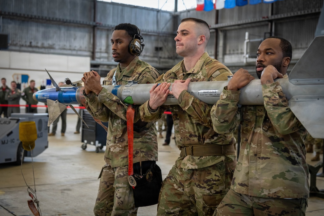 Three U.S. Air Force Airmen carry a missile.