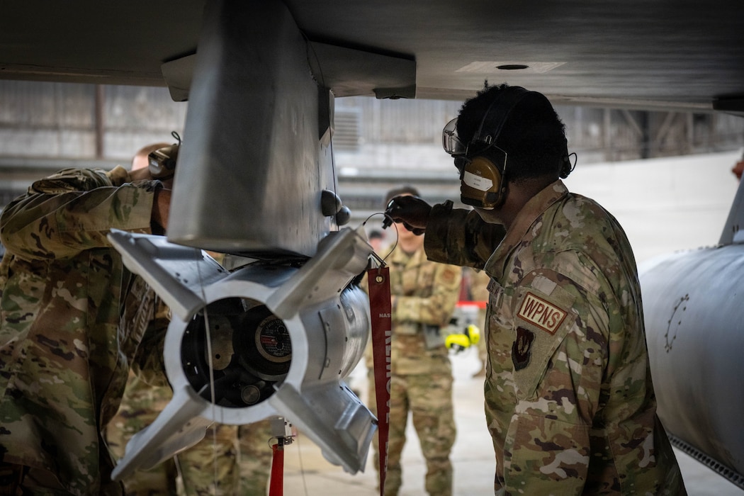 U.S. Air Force member checks a munition with a flashlight.