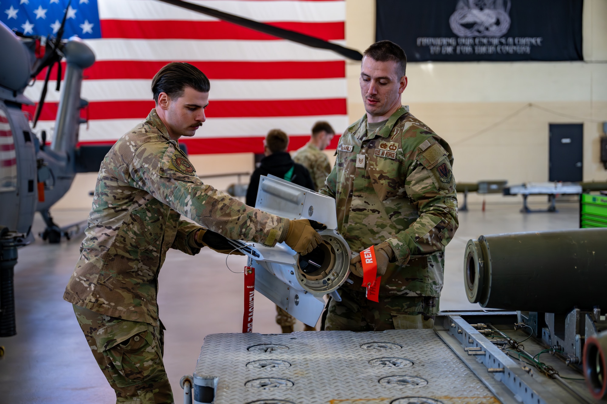 Two men lift equipment.