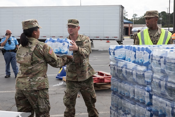 Georgia State Defense Force personnel and U.S. Army Soldiers with the Augusta-based 878th Engineer Battalion, 648th Maneuver Enhancement Brigade, Georgia Army National Guard, unload cases of water during a point of distribution (POD) mission in Augusta, Georgia, Sept. 30, 2024. The Georgia National Guard has mobilized to provide response and recovery support to areas in the state impacted by Hurricane Helene. At the direction of the Governor and through The Georgia Emergency Management and Homeland Security Agency (GEMA/HS), the Georgia National Guard will continue to partner local, state, and federal entities in this effort. (U.S. Army National Guard photo by Spc. Ayanna Tillman)